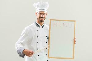 chefe de cozinha é mostrando quadro branco em cinzento fundo. foto