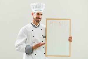 chefe de cozinha é mostrando quadro branco em cinzento fundo. foto