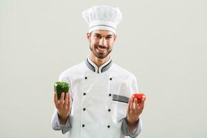 chefe de cozinha é mostrando legumes em cinzento fundo. foto