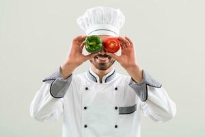 chefe de cozinha é tendo Diversão com legumes em cinzento fundo. foto