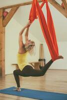 mulher fazendo aéreo ioga dentro a ginástica estúdio foto