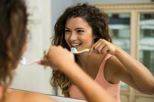 linda mulher escovando os dentes no banheiro foto