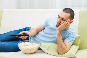 jovem homem é sentindo-me tédio e mudando canais em televisão foto