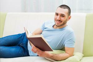 jovem homem goza lendo livro às dele casa foto