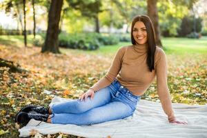 lindo mulher goza dentro outono enquanto em repouso dentro a parque foto