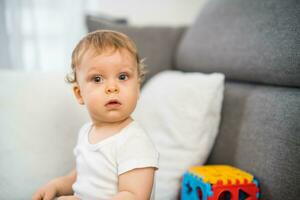 retrato do fofa pequeno bebê Garoto jogando enquanto sentado em sofá foto