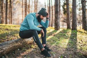 Exausta homem depois de exercício sentado dentro a natureza foto