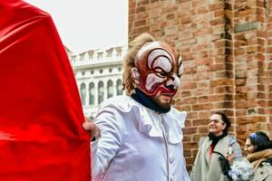 uma homem dentro uma palhaço mascarar segurando uma vermelho bandeira foto