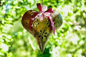 uma metal coração em forma decoração suspensão a partir de uma árvore foto