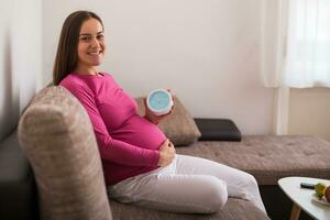 feliz grávida mulher grávida segurando relógio. foto