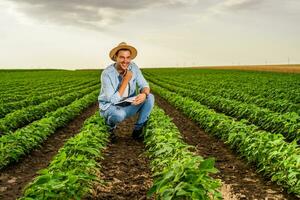 feliz agricultor gastos Tempo dentro dele crescendo soja campo foto