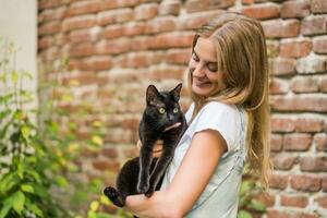 mulher e dela lindo Preto gato apreciar gastos Tempo juntos ao ar livre foto