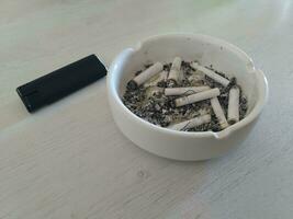 cigarro butts dentro cinzeiro em de madeira mesa. foto