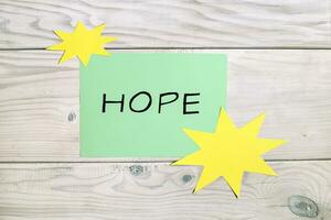 esperança palavra em papel com amarelo estrelas em de madeira fundo foto