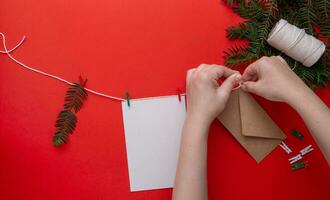 crianças mãos anexa a envelope para uma corda com uma Natal presente. foto