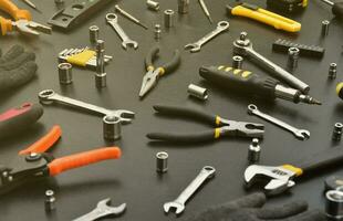 kit de ferramentas de faz-tudo na mesa de madeira preta. muitas chaves e chaves de fenda, empilhadeiras e outras ferramentas para qualquer tipo de reparo ou construção. ferramentas de reparador foto