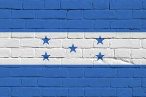 Honduras bandeira retratado dentro pintura cores em velho tijolo muro. texturizado bandeira em grande tijolo parede alvenaria fundo foto