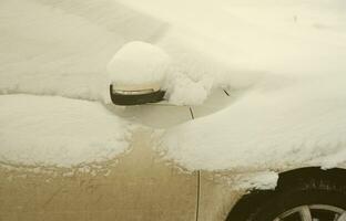 fragmento do carro sob uma camada de neve após uma forte nevasca. o corpo do carro está coberto de neve branca foto
