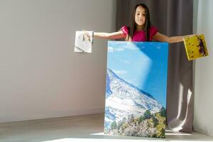 pequeno menina segurando tela de pintura dentro a interior foto