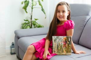 pequeno menina segurando tela de pintura dentro a interior foto