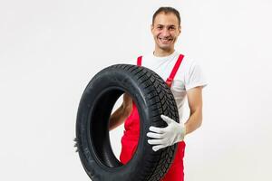 retrato do sorridente masculino mecânico segurando pneu em branco fundo foto