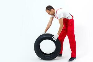 mecânico segurando um pneu na oficina. substituição dos pneus de inverno e verão. foto