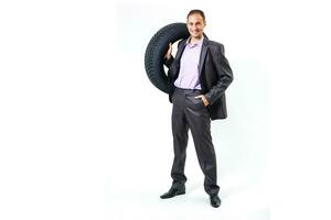 cheio comprimento retrato do uma jovem homem de negocios inclinado em uma pilha do carro pneus isolado em branco fundo foto