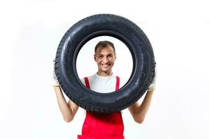 retrato do sorridente masculino mecânico segurando pneu em branco fundo foto