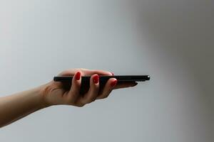 fechar-se tiro do uma mulher mostrando Móvel telefone isolado em branco fundo. fêmea mão segurando uma moderno Smartphone. mão mostrando uma branco telefone tela. foto