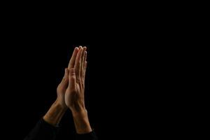 homem bonito sente oração em fundo preto. suas mãos estão orando pelas bênçãos de Deus. foto