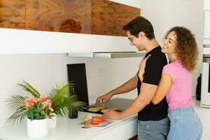 feliz adulto homem em pé perto cozinhando alcance e sorridente mulher abraçando a partir de atrás foto