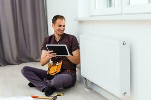 homem é reparação radiador bateria dentro a sala. manutenção reparar trabalho renovação dentro a plano. aquecimento restauração. chave inglesa dentro mãos. foto