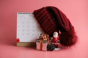 presente caixa e calendário com uma vermelho tricotado lã chapéu em Rosa fundo. Natal dia conceito. planejamento agendamento agenda, evento, organizador x'mas dia. foto
