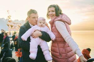 ao ar livre retrato do feliz família com adorável bebê menina às Natal mercado foto