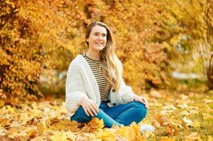 outono retrato do jovem feliz menina sentado em terra com amarelo folhagem fundo, saudável estilo de vida foto