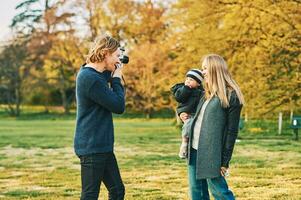 fotógrafo levando filme As fotos do jovem moder com criança pequena menina dentro outono ou Primavera parque