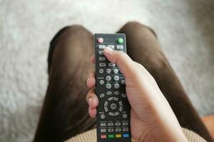 close-up da mão de mulheres segurando o controle remoto da tv. foto