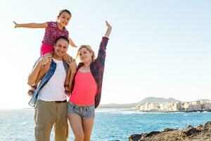 feliz jovem família ter Diversão em de praia corre e saltar às pôr do sol foto