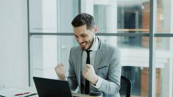 jovem homem de negocios usando computador portátil computador recebendo Boa mensagem e tornar-se muito animado e feliz senta dentro moderno escritório dentro de casa foto