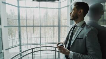 jovem bonito homem de negocios dentro terno bebendo café comovente acima dentro elevador dentro moderno o negócio Centro dentro de casa foto