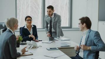 empresária discutindo relatórios com masculino e fêmea colegas sentado às a mesa dentro moderno escritório dentro de casa foto