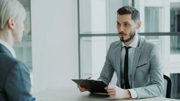 hr masculino Gerente tendo trabalho entrevista com jovem mulher dentro terno e assistindo dela currículo inscrição dentro moderno escritório dentro de casa foto