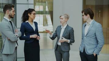 empresária falando para dela colegas enquanto em pé dentro escritório lobby dentro de casa. grupo do o negócio pessoas discutindo futuro acordo foto