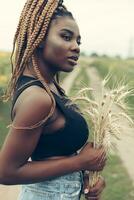 africano americano menina dentro uma campo do amarelo flores às pôr do sol foto