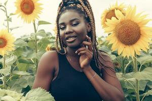 africano americano menina dentro uma campo do amarelo flores às pôr do sol foto