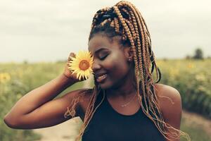 africano americano menina dentro uma campo do amarelo flores às pôr do sol foto