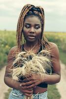 africano americano menina dentro uma campo do amarelo flores às pôr do sol foto