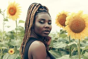 africano americano menina dentro uma campo do amarelo flores às pôr do sol foto