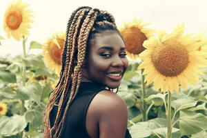 africano americano menina dentro uma campo do amarelo flores às pôr do sol foto