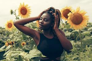 africano americano menina dentro uma campo do amarelo flores às pôr do sol foto